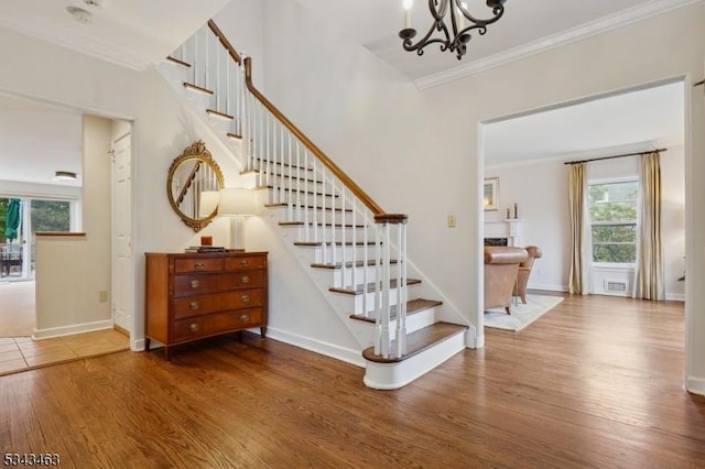 stairway with baseboards, wood finished floors, and crown molding