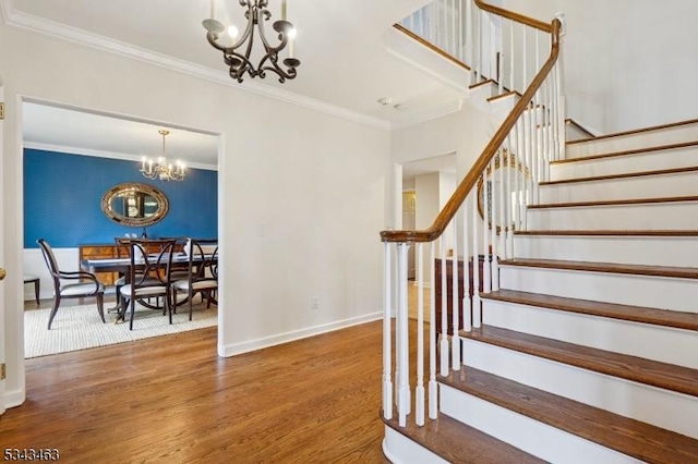 stairs featuring baseboards, wood finished floors, a notable chandelier, and ornamental molding