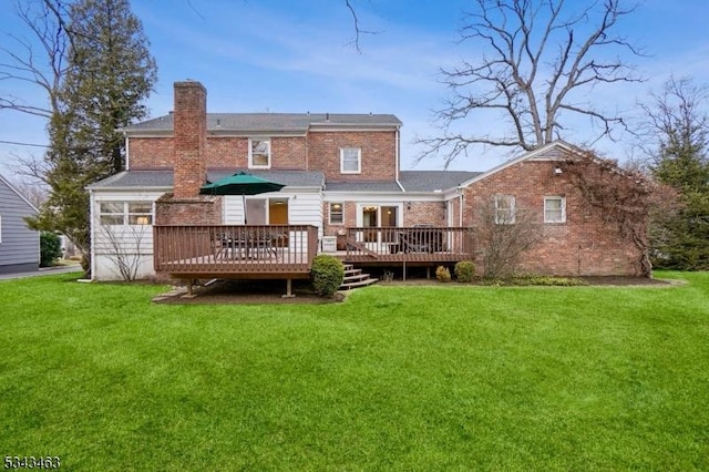 rear view of property featuring brick siding, a lawn, a deck, and a chimney