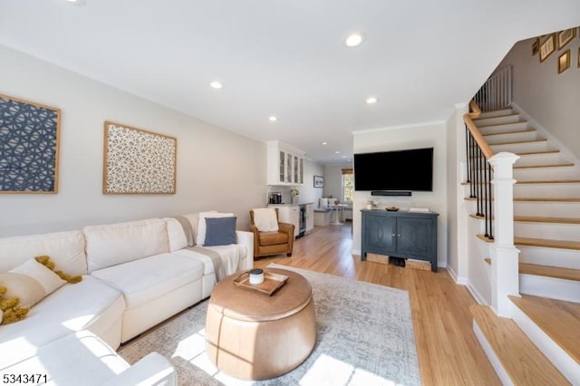 living room with recessed lighting, light wood-style flooring, stairs, and baseboards