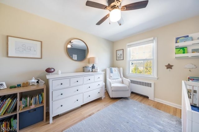 sitting room with ceiling fan, radiator, baseboards, and light wood-style floors