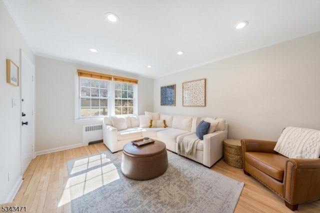 living room featuring baseboards, radiator heating unit, recessed lighting, crown molding, and light wood-type flooring