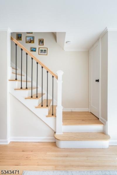 staircase featuring baseboards, wood finished floors, and ornamental molding