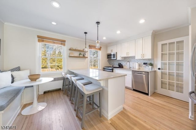 kitchen with ornamental molding, stainless steel appliances, white cabinets, a kitchen bar, and breakfast area