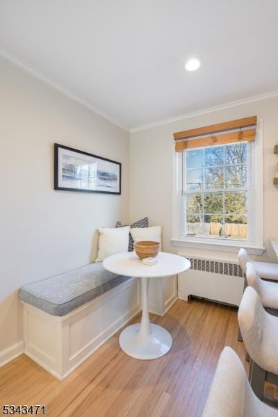 bedroom featuring light wood-style flooring, crown molding, radiator heating unit, and baseboards