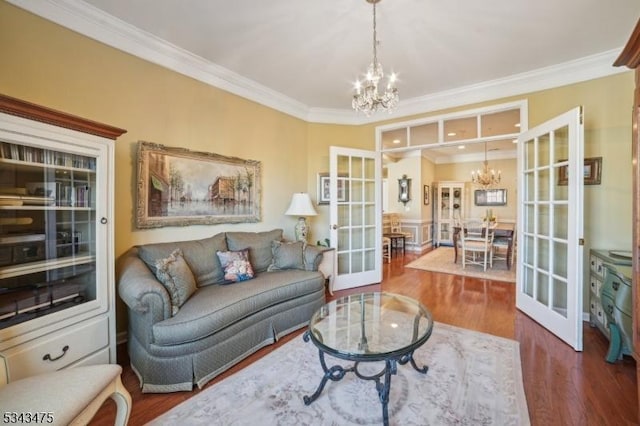 living room with a notable chandelier, french doors, crown molding, and wood finished floors