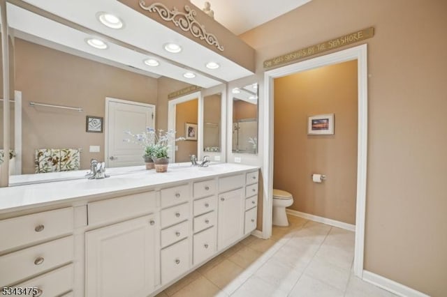 bathroom with tile patterned flooring, baseboards, toilet, double vanity, and a sink