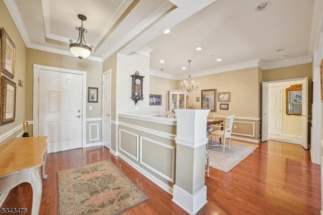 foyer with wood finished floors, a wainscoted wall, recessed lighting, crown molding, and a decorative wall