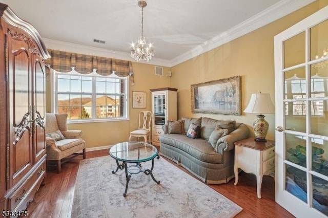 living area featuring visible vents, wood finished floors, an inviting chandelier, and ornamental molding