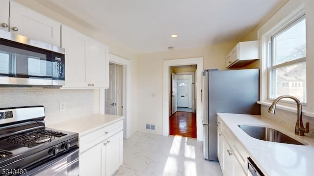 kitchen with visible vents, appliances with stainless steel finishes, white cabinets, marble finish floor, and a sink