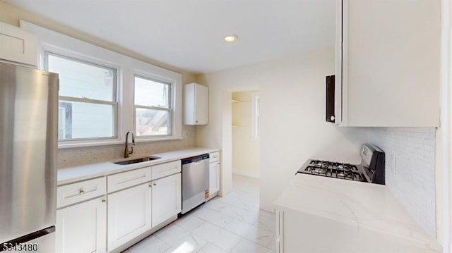 kitchen featuring a sink, stainless steel appliances, marble finish floor, and white cabinets