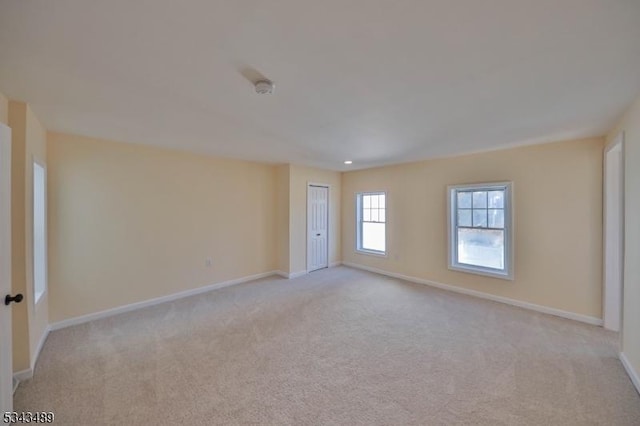 spare room with light colored carpet and baseboards