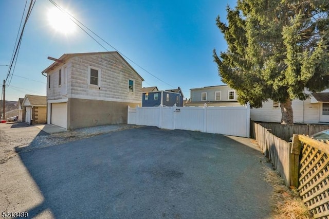 view of side of property featuring a garage, driveway, and fence