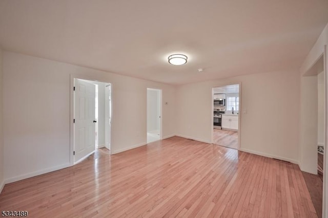 unfurnished room featuring baseboards and light wood finished floors