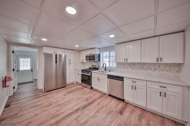 kitchen featuring a sink, stainless steel appliances, light countertops, white cabinets, and tasteful backsplash