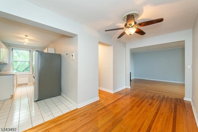 kitchen with freestanding refrigerator, a ceiling fan, baseboards, and light wood-style flooring