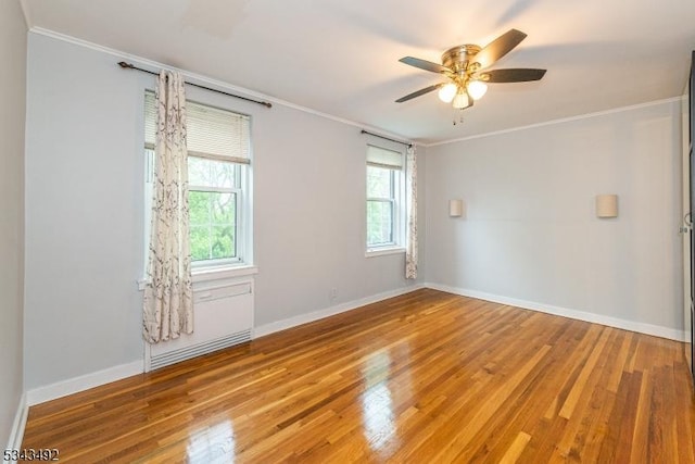 empty room with ornamental molding, wood finished floors, baseboards, and a ceiling fan