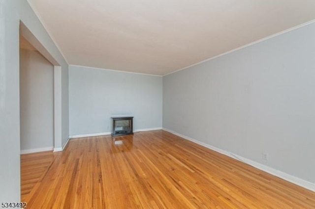 unfurnished living room featuring wood finished floors, ornamental molding, baseboards, and a fireplace