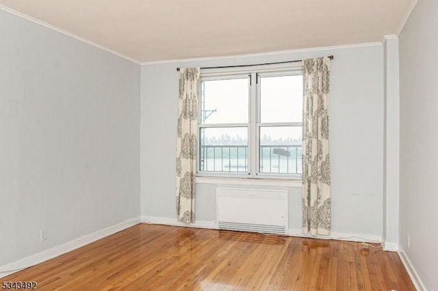 spare room with light wood-style flooring, baseboards, and crown molding