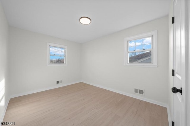 spare room featuring visible vents, plenty of natural light, and light wood-style floors