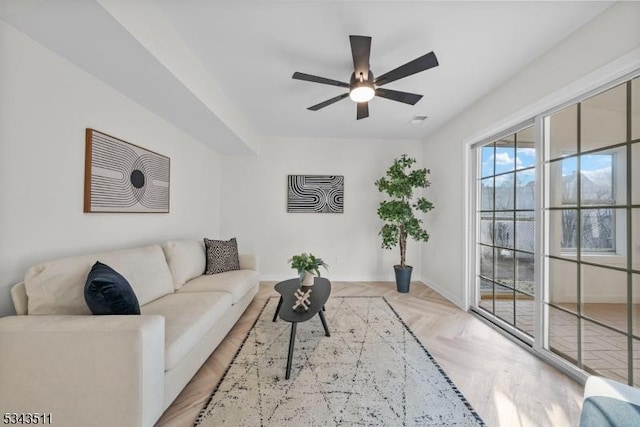 living area featuring visible vents, baseboards, and ceiling fan