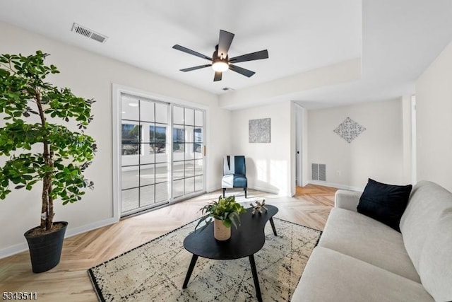 living area featuring a ceiling fan, visible vents, and baseboards