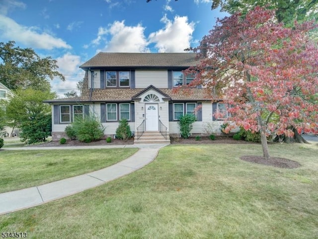 view of front of house with a front yard and roof with shingles