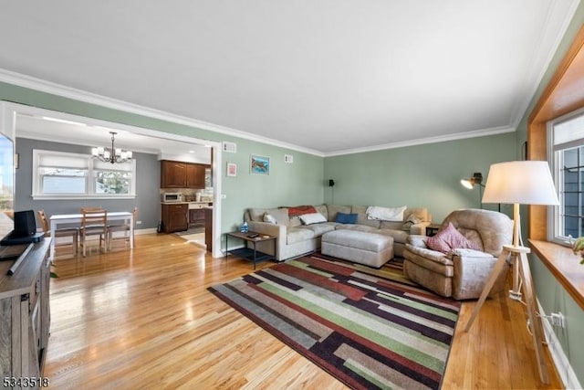 living room featuring light wood-type flooring, a chandelier, and crown molding