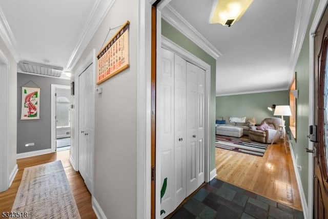 hallway featuring baseboards, wood finished floors, and crown molding