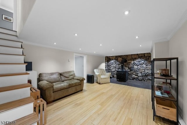 living area with stairs, ornamental molding, recessed lighting, a wood stove, and wood finished floors