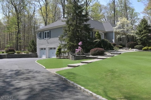 view of front of property featuring aphalt driveway, a front lawn, and a garage
