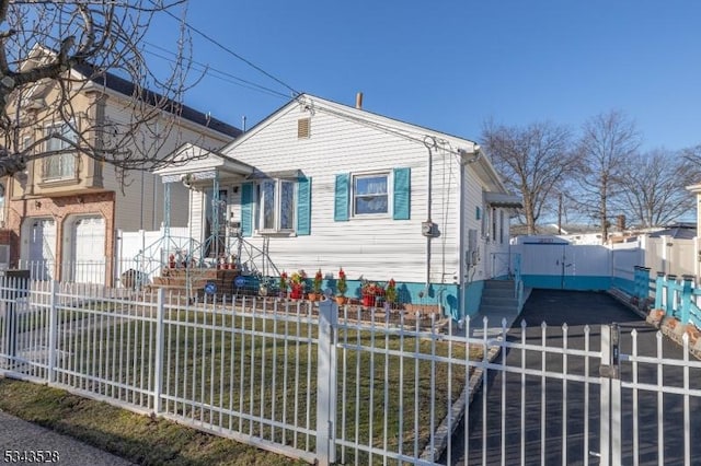 bungalow with a fenced front yard, concrete driveway, and an attached garage