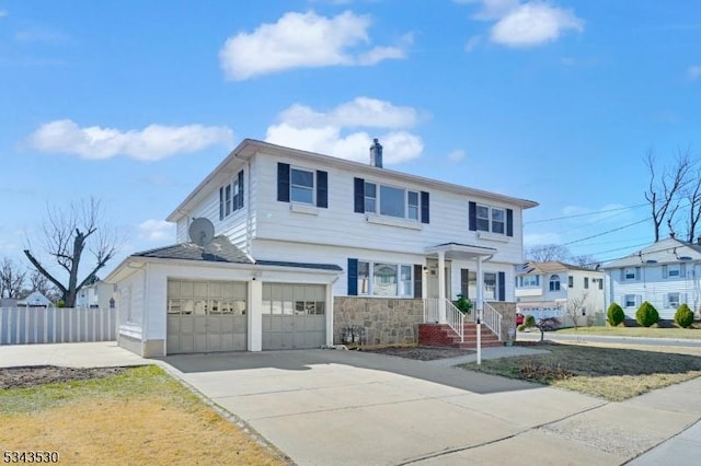 traditional-style home featuring driveway, an attached garage, and fence