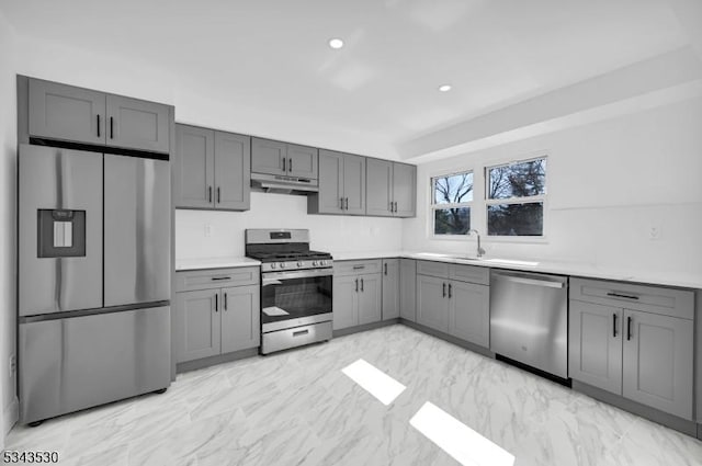 kitchen with marble finish floor, gray cabinetry, under cabinet range hood, appliances with stainless steel finishes, and light countertops