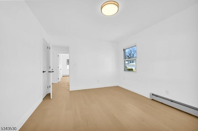 empty room with light wood finished floors, baseboards, and baseboard heating