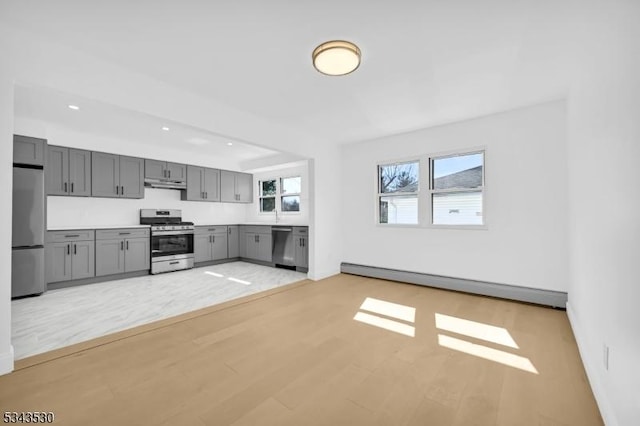 kitchen with gray cabinetry, light wood-style flooring, under cabinet range hood, stainless steel appliances, and a baseboard radiator