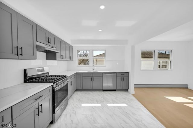 kitchen featuring gray cabinetry, a baseboard heating unit, under cabinet range hood, recessed lighting, and appliances with stainless steel finishes