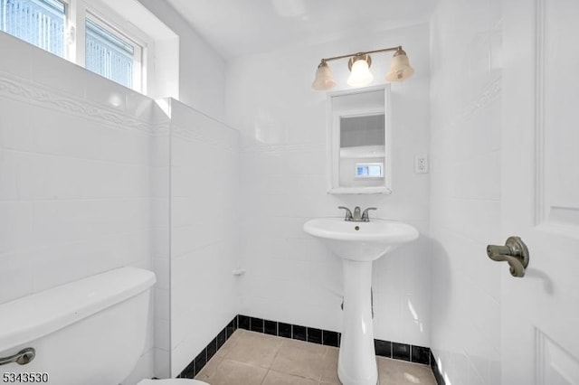 bathroom with toilet, tile walls, and tile patterned flooring