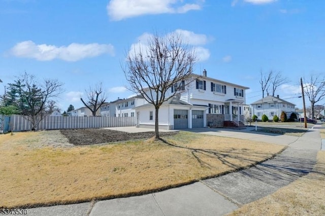 view of front of house featuring a front yard, an attached garage, fence, and driveway