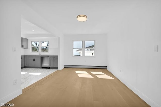 unfurnished living room featuring light wood-type flooring, a baseboard heating unit, baseboards, and a sink