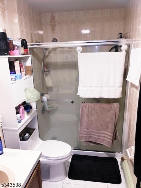 bathroom with tile patterned flooring, a shower stall, toilet, and vanity