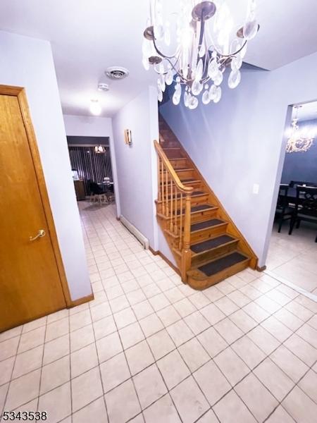 staircase featuring visible vents, baseboards, a notable chandelier, and tile patterned flooring