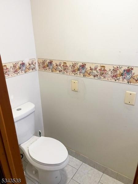 bathroom featuring tile patterned flooring, a wainscoted wall, and toilet