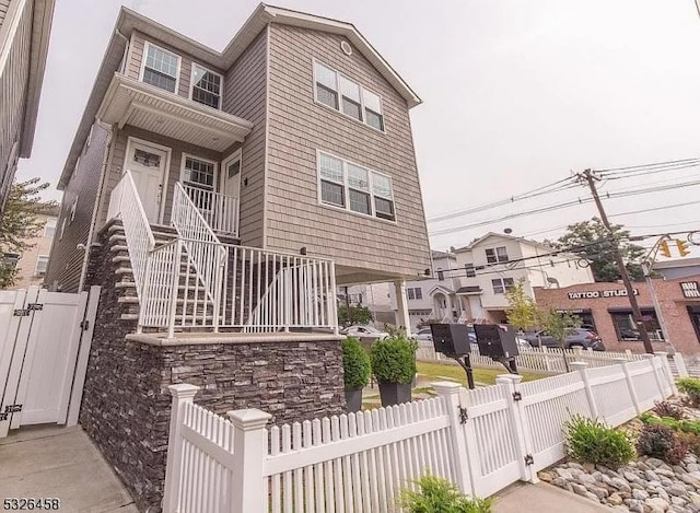 view of property featuring a fenced front yard, stairway, and a gate