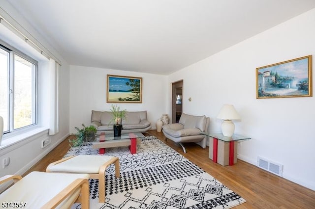 living area with visible vents, baseboards, and wood finished floors