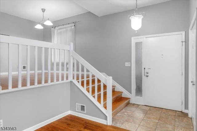 foyer entrance featuring visible vents, baseboards, and stairway