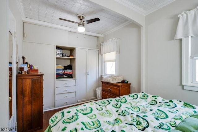 bedroom featuring ornamental molding, a ceiling fan, wood finished floors, a closet, and arched walkways