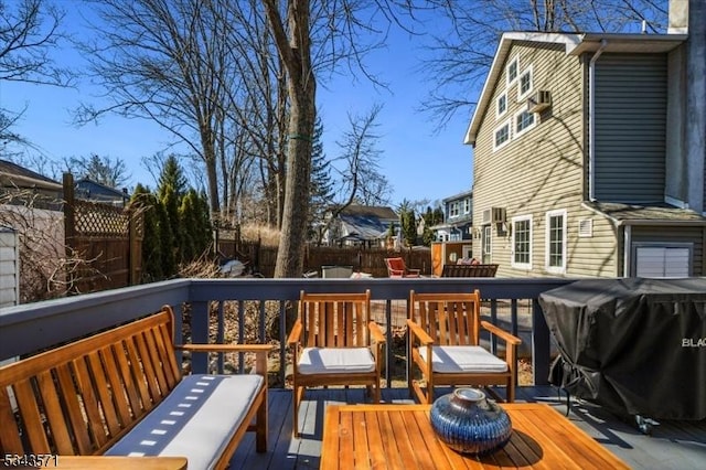 wooden deck with area for grilling and a fenced backyard