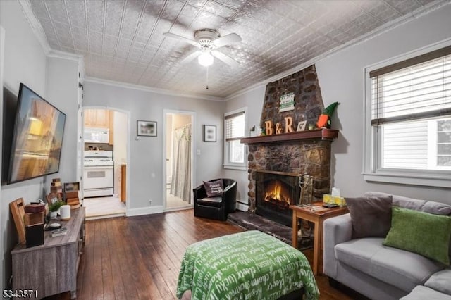 living room featuring ornamental molding, a fireplace, dark wood-style floors, an ornate ceiling, and a ceiling fan