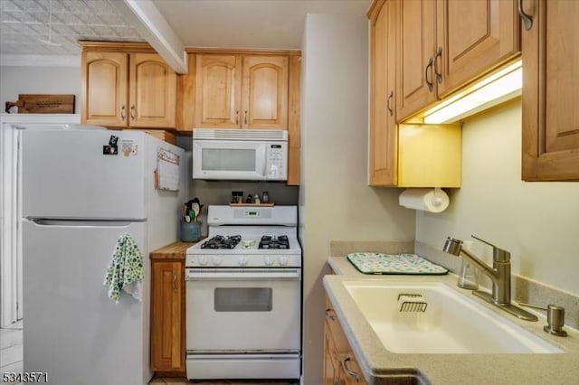 kitchen with a sink, white appliances, ornamental molding, and light countertops